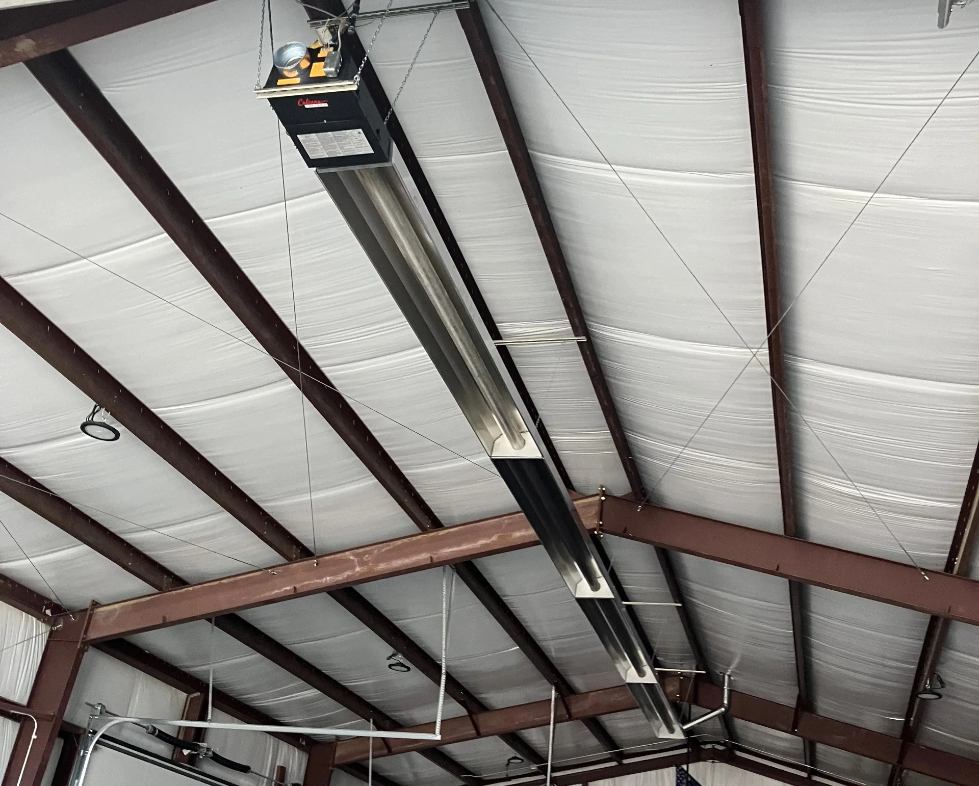 Radiant tube heater mounted to garage ceiling structure showing professional installation and optimal heat distribution for large spaces