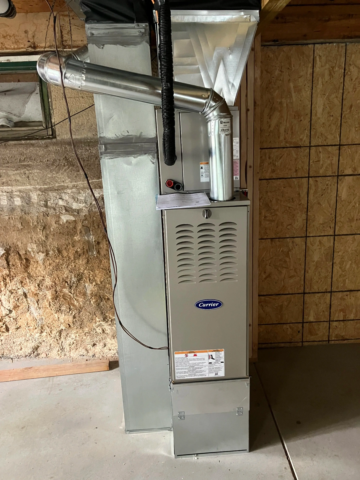 Professional Carrier furnace installation in basement showing proper installation techniques and clean ductwork connections