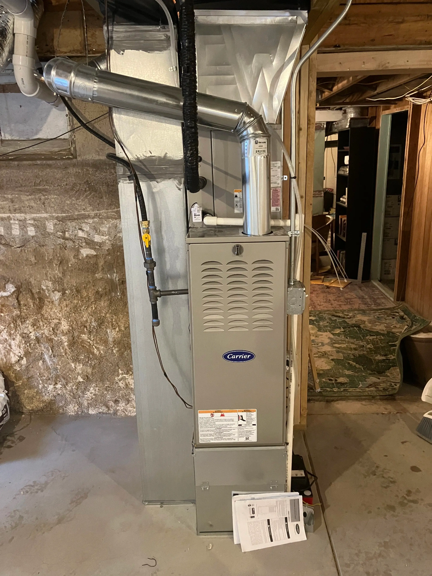 Complete Carrier furnace installation in basement showing professional workmanship, clean installation, and proper safety labeling